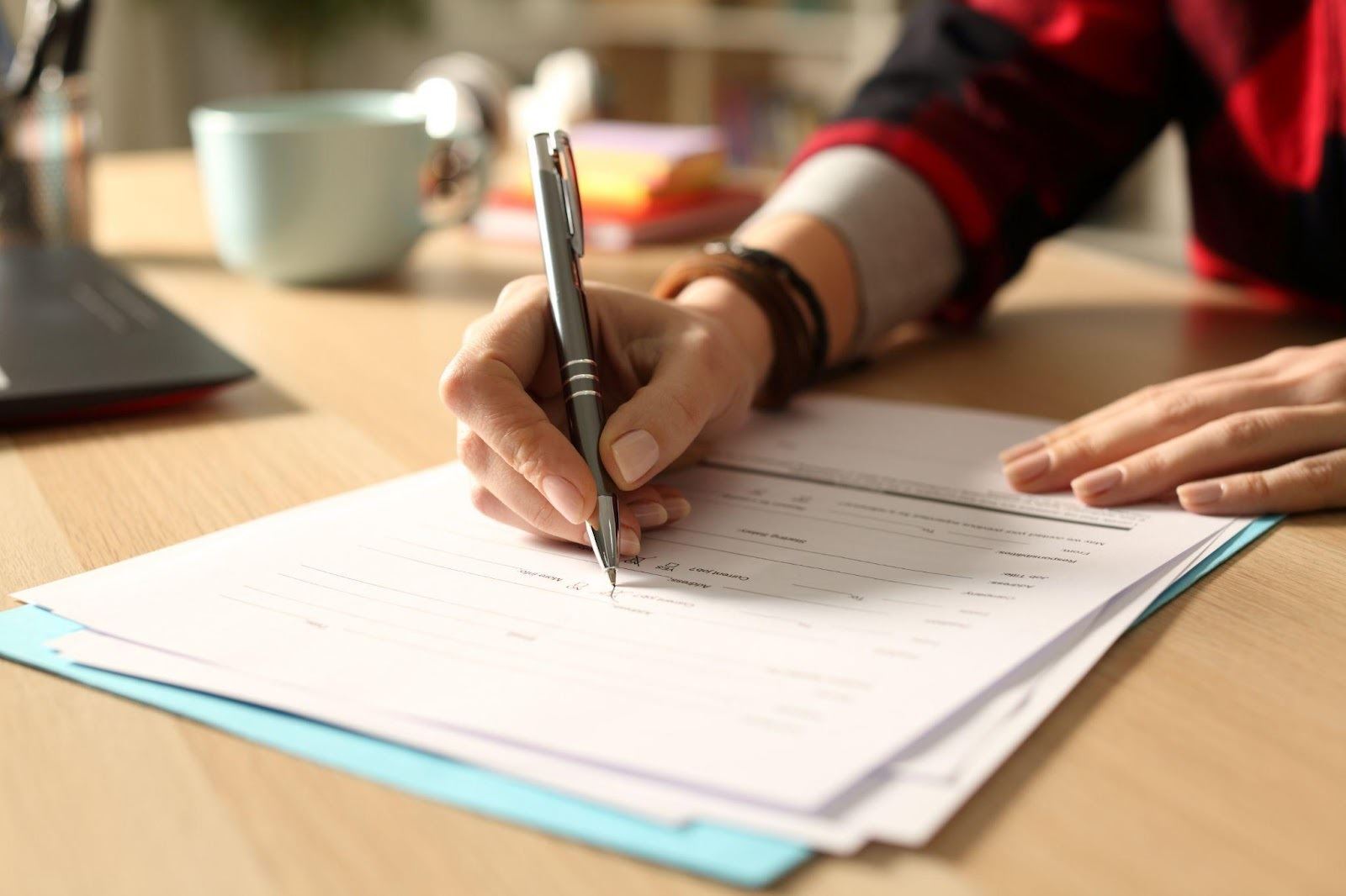 A hand holding a pen and writing on a piece of paper