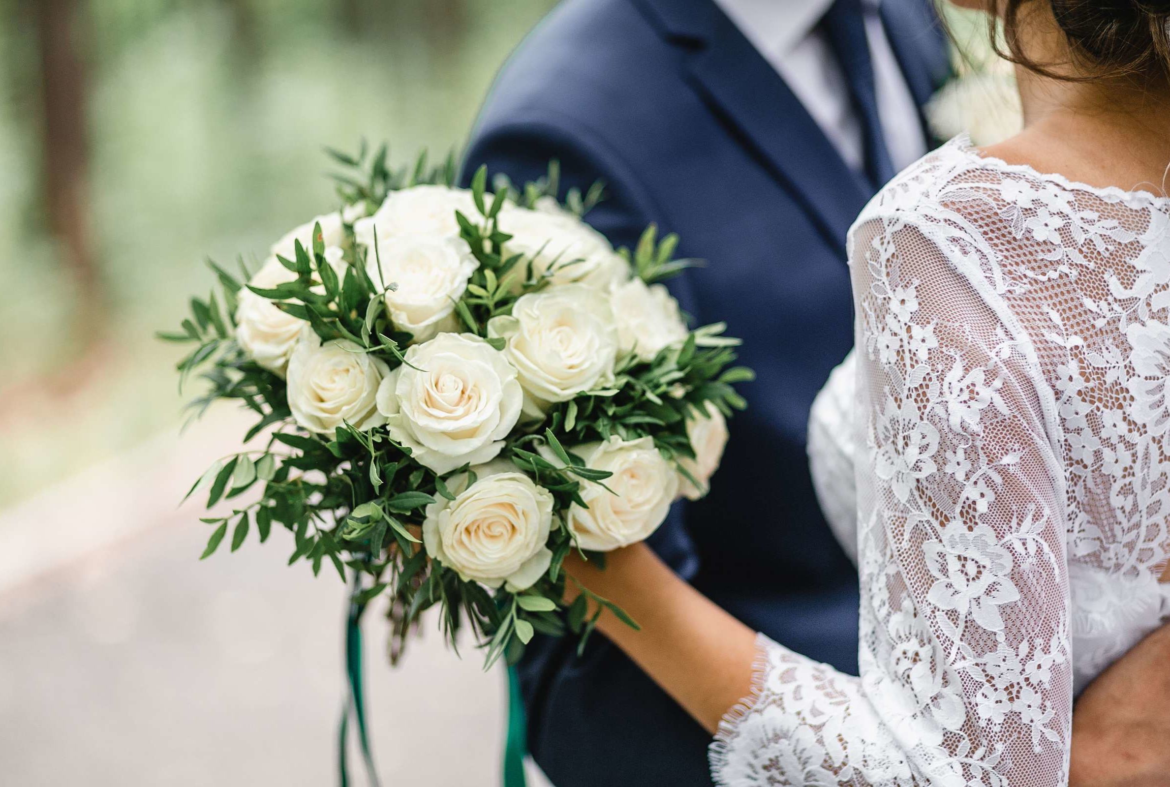 A bride and groom holding white roses, symbolizing love and purity on their wedding day.