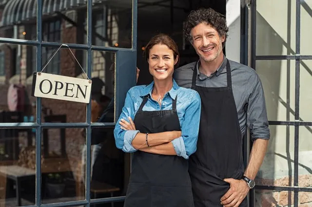 A man and woman standing outside a business.